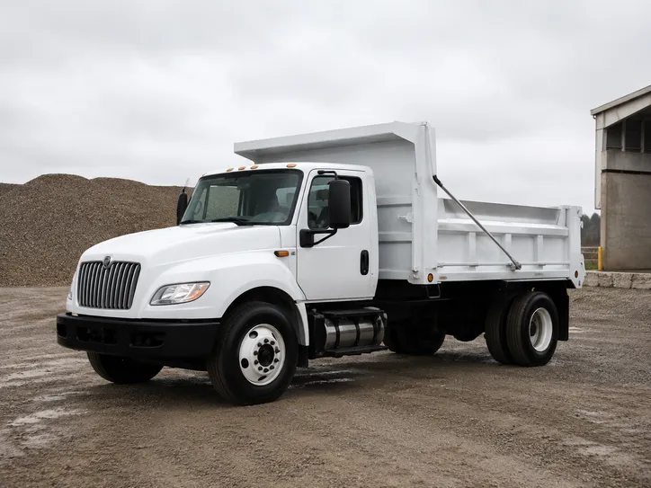 White dump truck parked beside gravel piles at a material yard