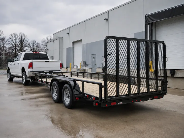 Open flatbed utility trailer with a wooden deck and ramp gate behind a pickup truck